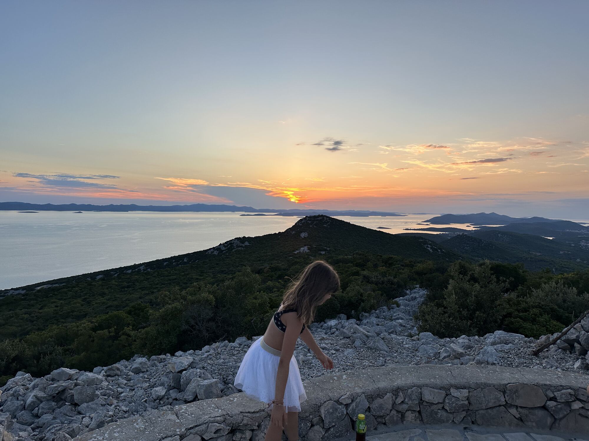 Sunset over the islands from Veliki Bokolj, with a child watching
